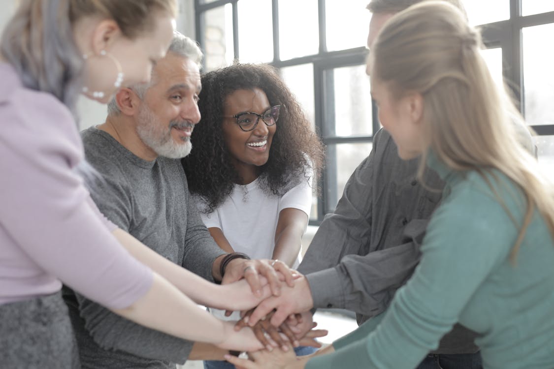 Content multiethnic colleagues joining hands after coming to agreement