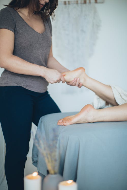 A Woman in Gray Shirt and Black Pants Massaging a Foot
