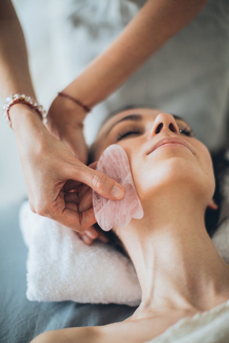 A Person Touching A Woman's Face Using Gua Sha