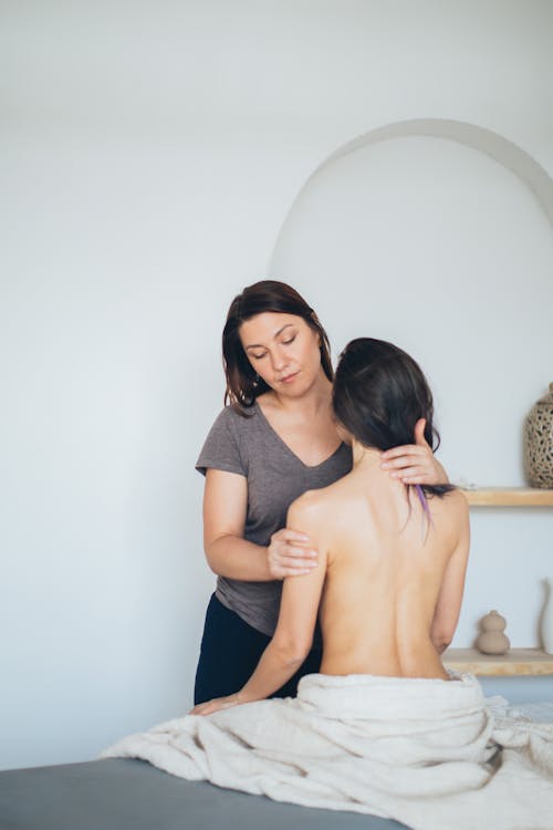 A Woman in Gray Shirt Massaging a Topless Woman