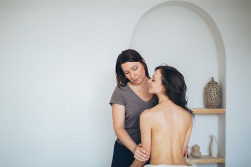 Free A Woman in Gray Shirt Holding a Topless Woman's Arms Stock Photo