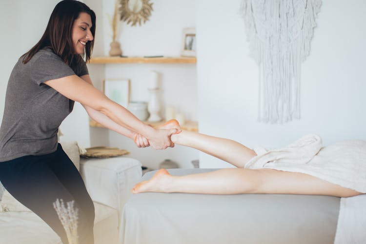 A Woman In Gray Shirt Pulling A Person's Leg