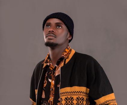 Portrait of a young man dressed in patterned attire looking upwards, exuding confidence and style.