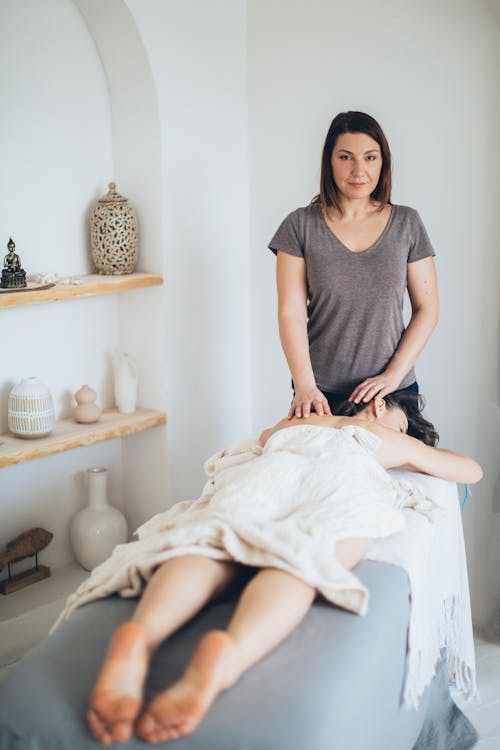 A Woman in Gray Shirt Standing Near the Woman Lying Down