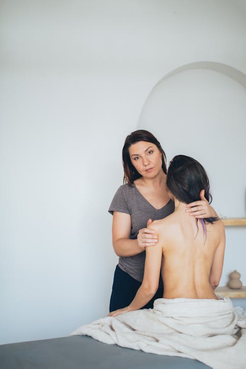 A Woman in Gray Shirt Massaging a Topless Woman