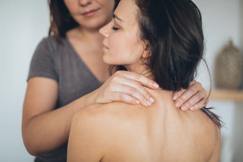 A Person Massaging a Topless Woman