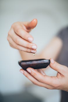 A close-up shot of hands dripping oil into a wooden bowl, signifying relaxation and wellness.