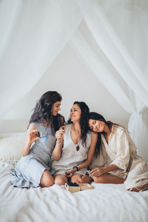 Free Three women sitting on a bed, enjoying a relaxing conversation indoors. Stock Photo