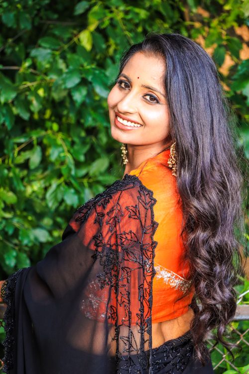 Free Beautiful woman in a traditional saree smiles brightly in a lush outdoor setting. Stock Photo
