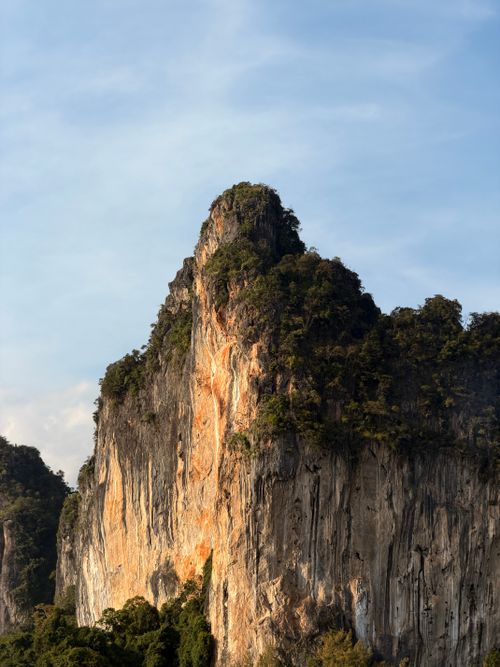 Free Dramatic limestone cliffs covered with lush greenery under a clear blue sky in Thailand. Stock Photo