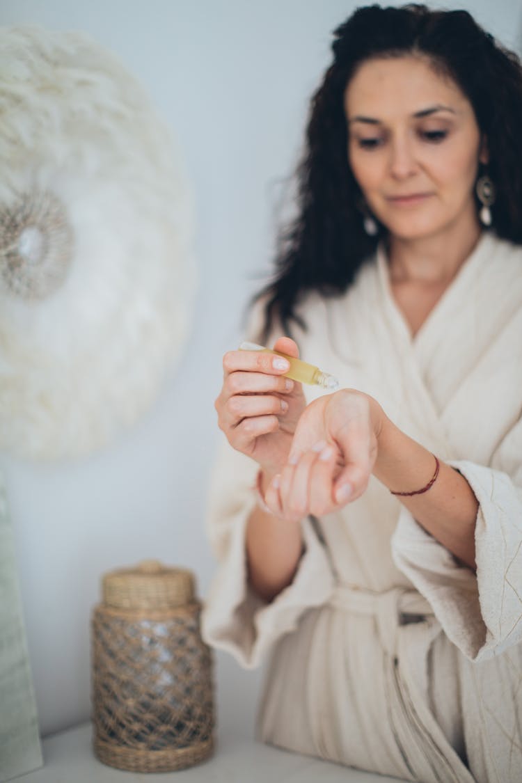 A Woman In Bathrobe Putting A Perfume On Her Pulse