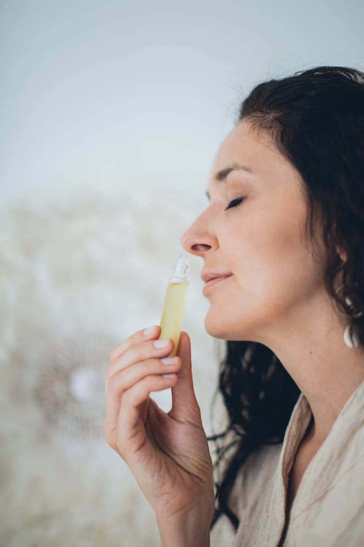 A Woman Smelling A Perfume With Her Eyes Closed