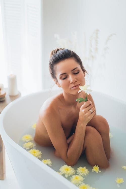 A Naked Woman in Bathtub holding a Flower