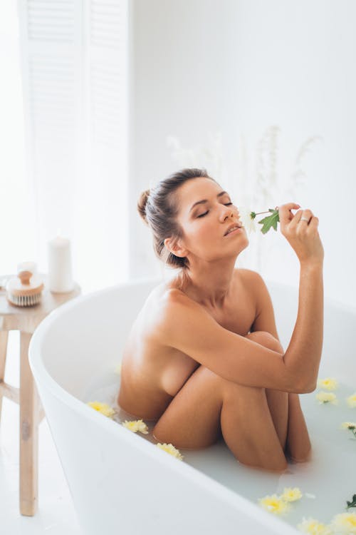Naked Woman in Bathtub Smelling a Flower