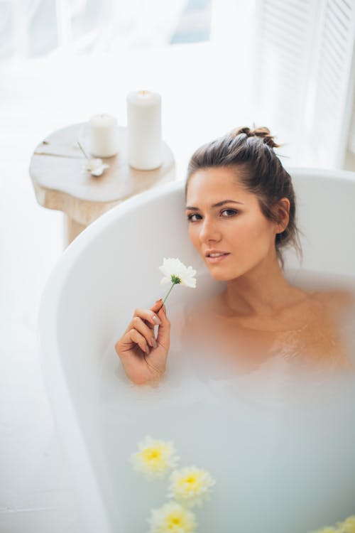 A Beautiful Woman in bathtub Holding a Flower