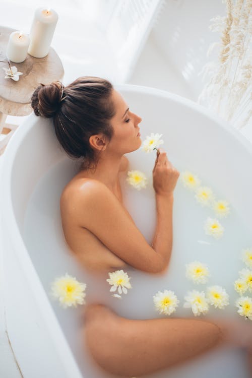 Topless Woman in Bathtub With White Daisy Flowers