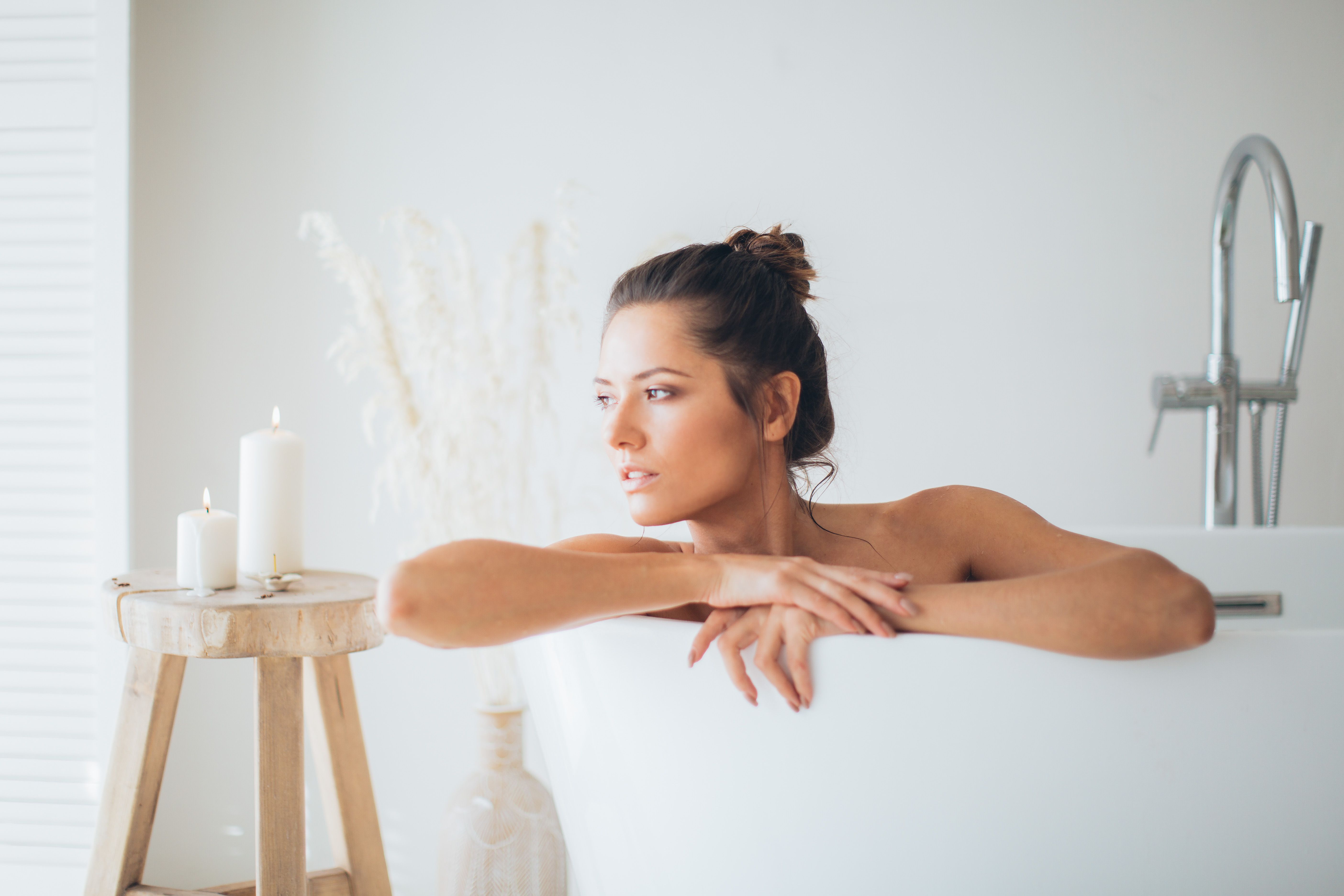 A woman relaxing in a bathtub with lit candles, enjoying a peaceful moment indoors.