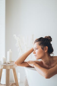 Serene moment of a woman enjoying relaxation in a candlelit bathtub.