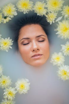 一位安静的女子闭着双眼，在铺满黄色花朵的豪华牛奶浴中沐浴