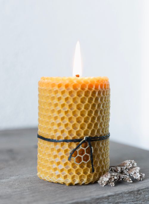 Free A handmade beeswax candle burning warmly on a rustic surface, ideal for cozy atmospheres. Stock Photo