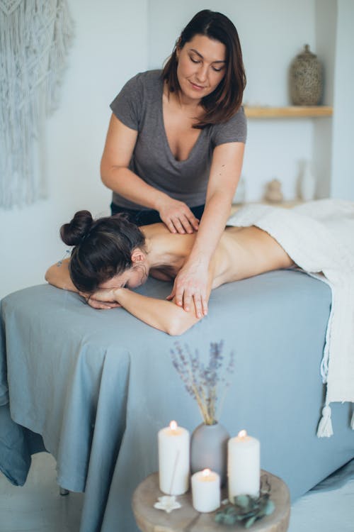 Free Woman Lying on Bed While Having A Massage Stock Photo