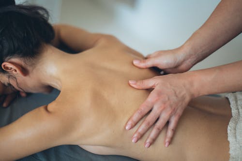 Free Topless woman Lying on Bed Getting Massage Stock Photo