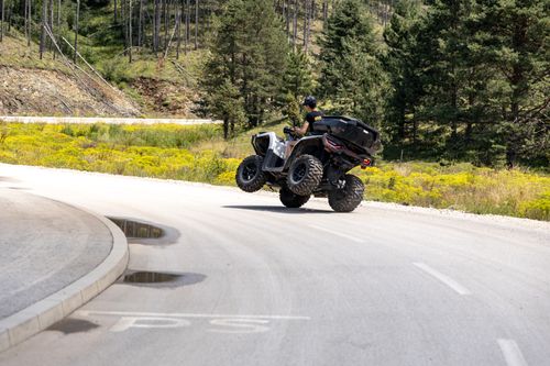 Free Thrilling ATV maneuver on a scenic mountain road in Zlatibor, Serbia, surrounded by lush greenery and vibrant summer scenery. Stock Photo