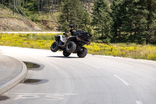 Free A thrilling scene of a man doing a wheelie on an ATV on a sunny day in the scenic landscape of Zlatibor, Serbia. Stock Photo