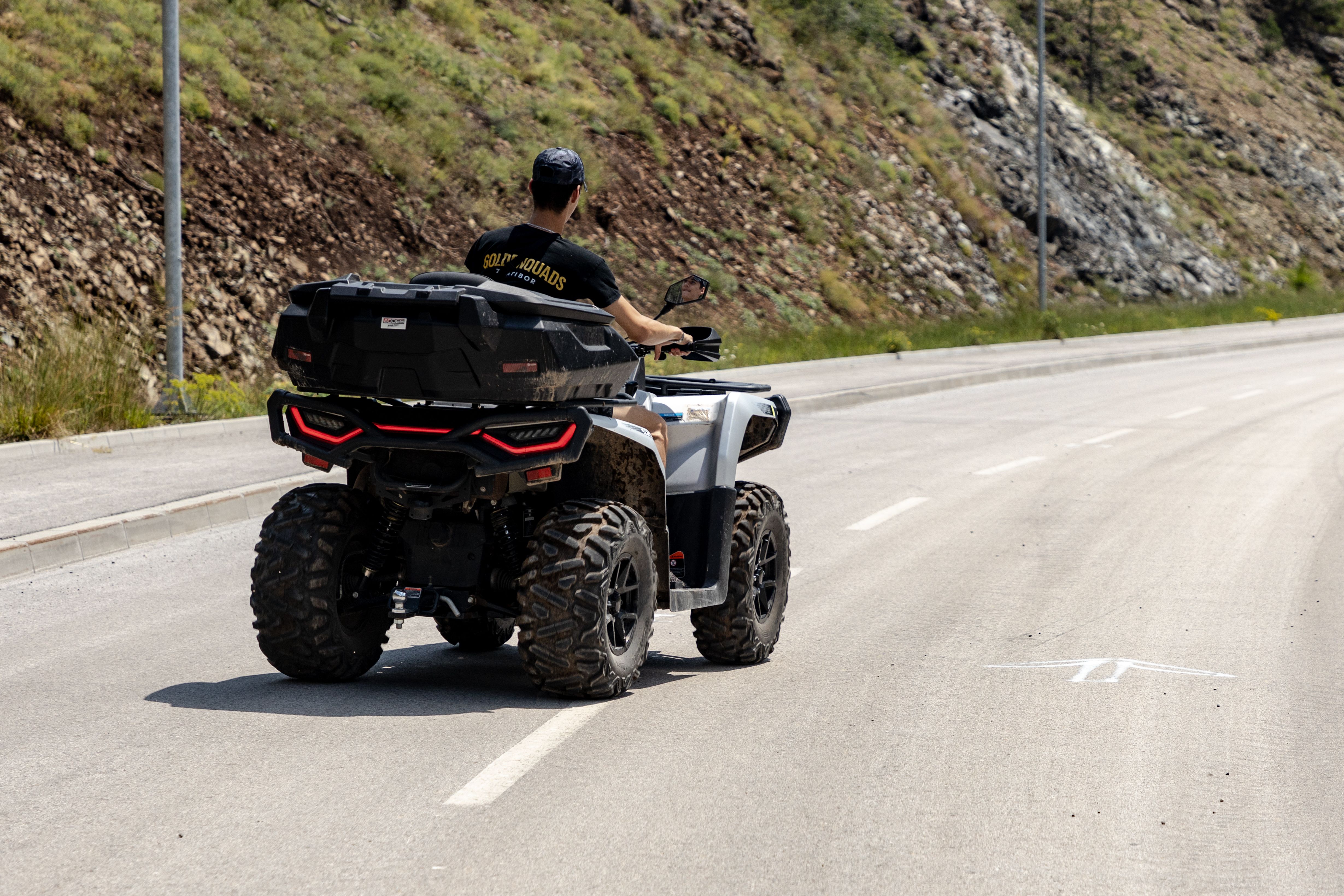 Person driving an ATV along a sunny mountain road in Zlatibor, Serbia, showcasing adventure and exploration.
