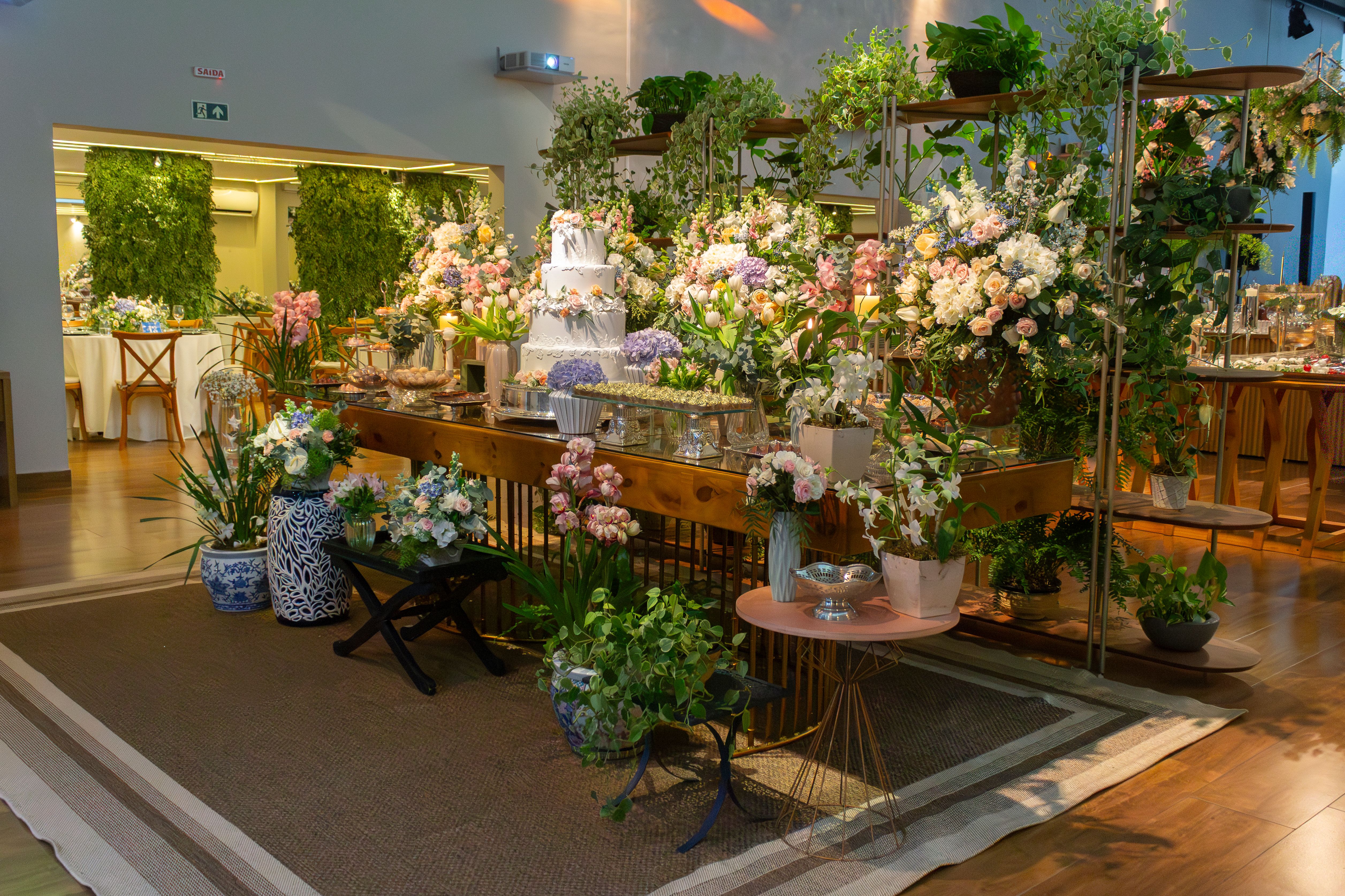 Beautiful floral arrangements and wedding cake at an indoor reception in São Paulo.