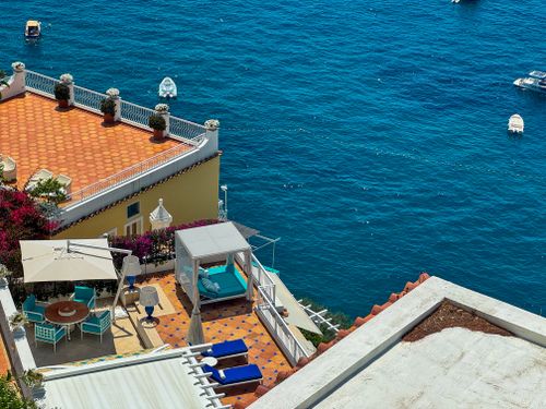 Free A terrace with vibrant furniture and loungers overlooking a blue sea, ideal for relaxation and summer leisure. Stock Photo