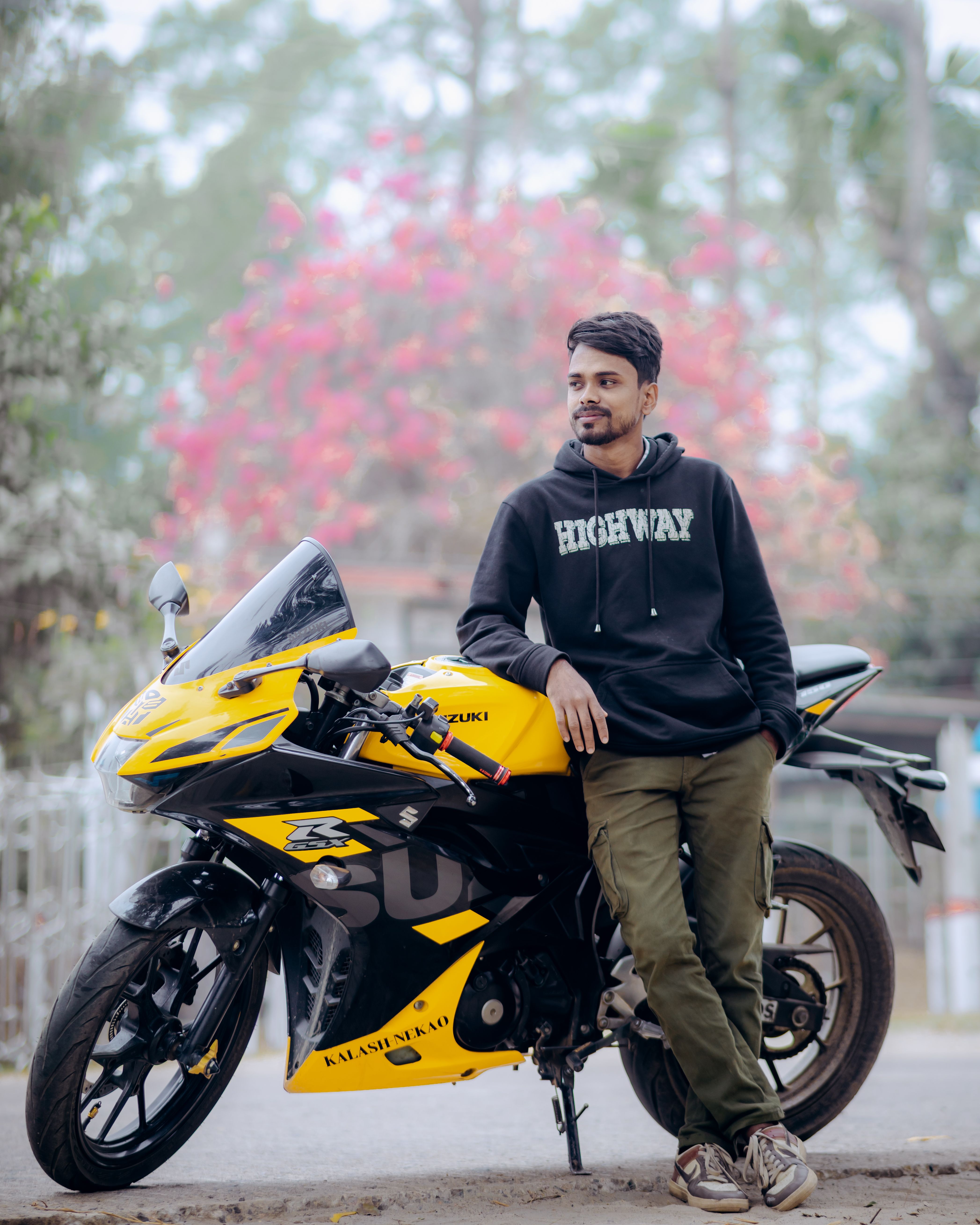 Man leaning on yellow sports bike in a casual pose, outdoor setting in Bangladesh.