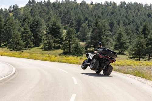 Free A thrilling moment as an ATV rider navigates a curvy mountain road near Zlatibor, surrounded by lush pine forests. Stock Photo