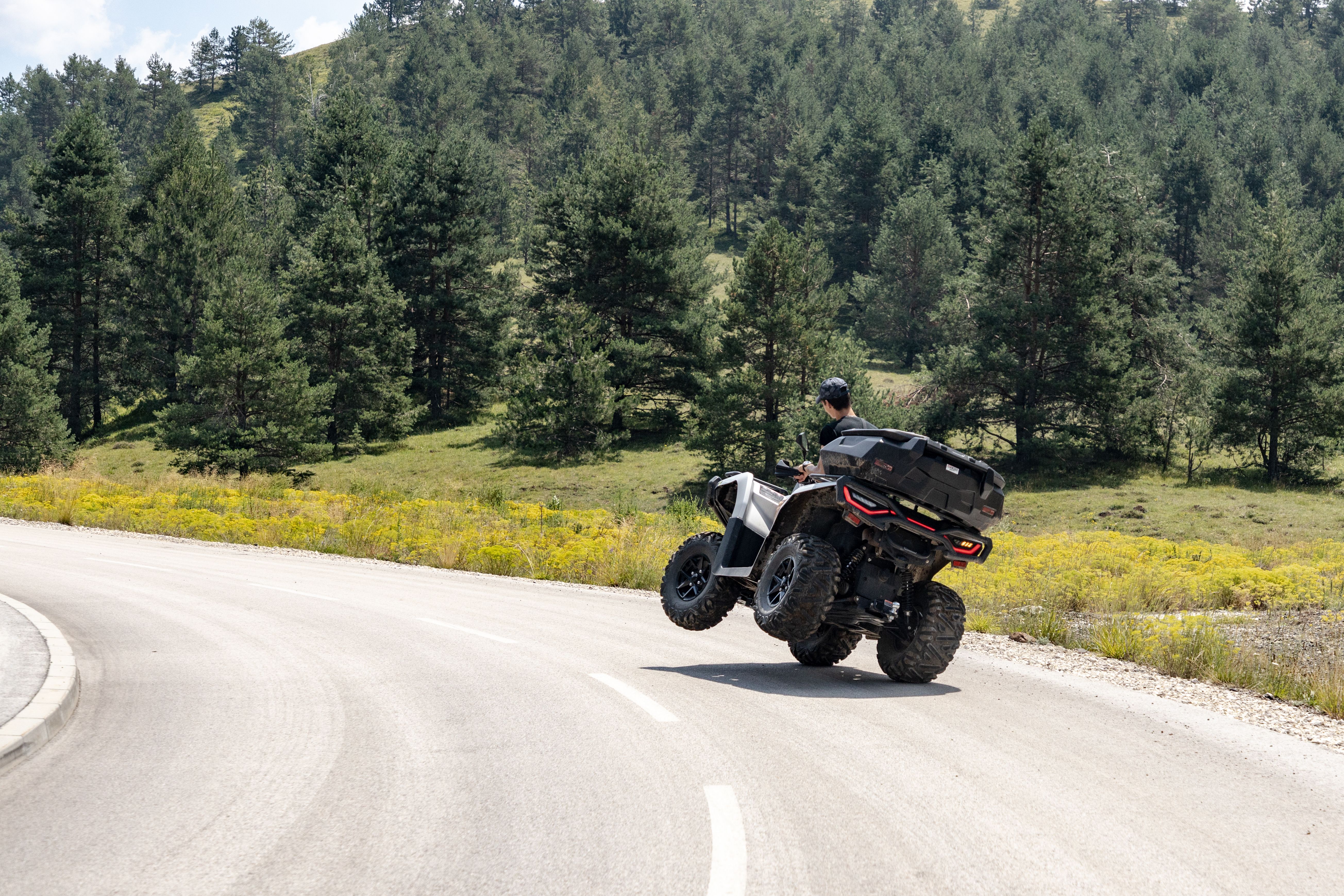 Off-road ATV riding on a scenic mountain road surrounded by lush greenery in Zlatibor, Serbia.
