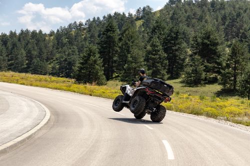 Free Exhilarating ATV ride on a scenic winding road in Zlatibor, Serbia, with lush green forest backdrop. Stock Photo