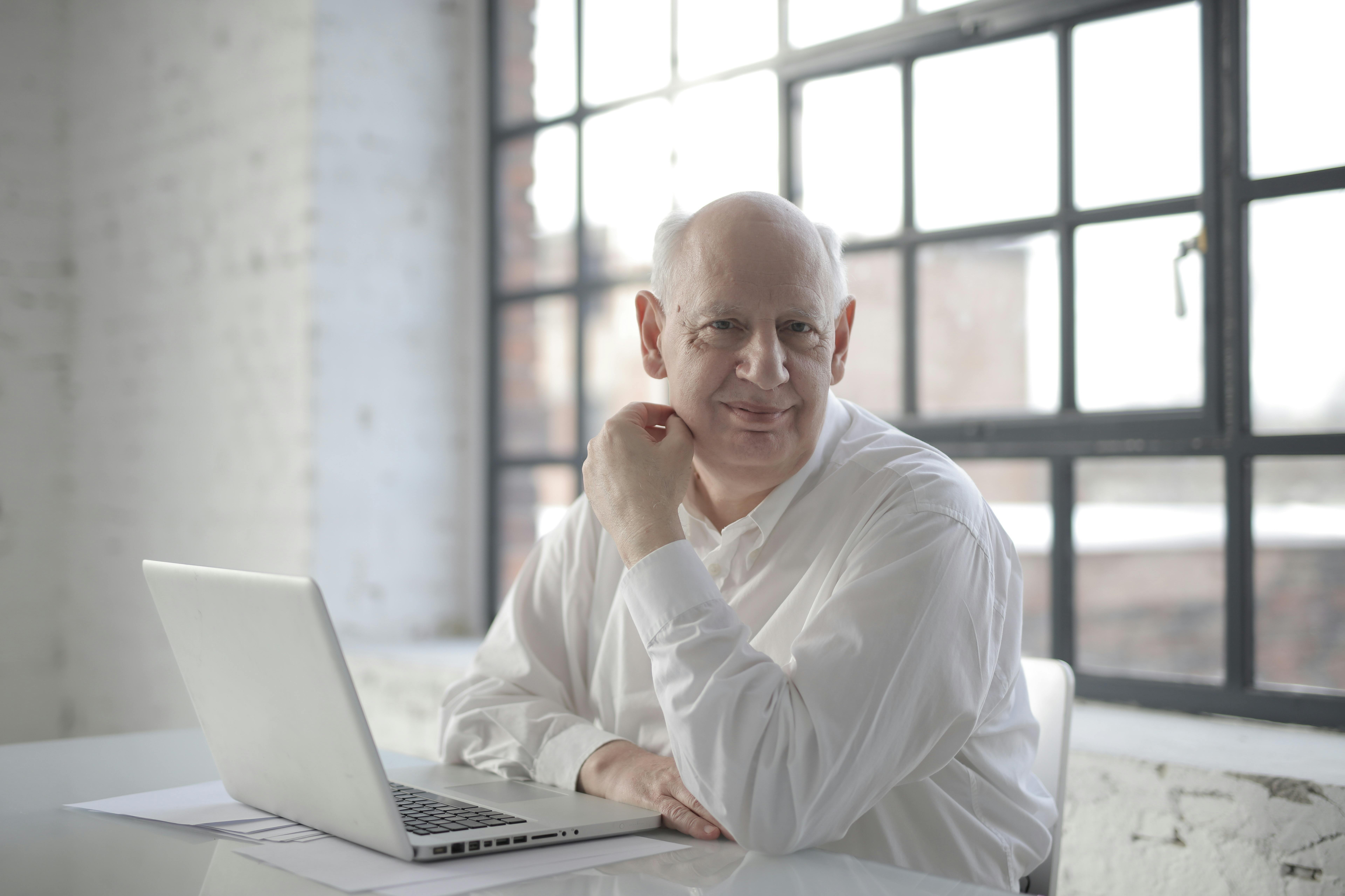 senior businessman with laptop and papers in creative workplace