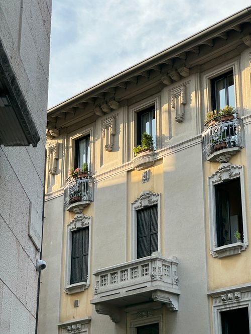 Free A beautiful Italian building showcasing classic architectural details and balconies with plants. Stock Photo