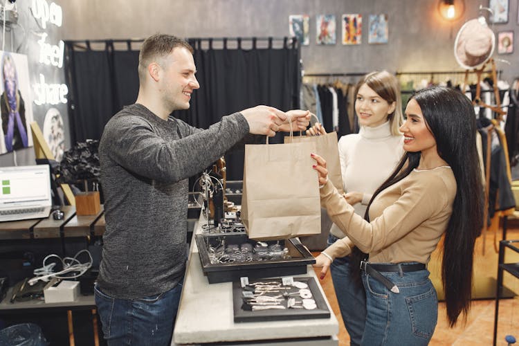 Female Customers Getting Paper Bags At Counter Desk