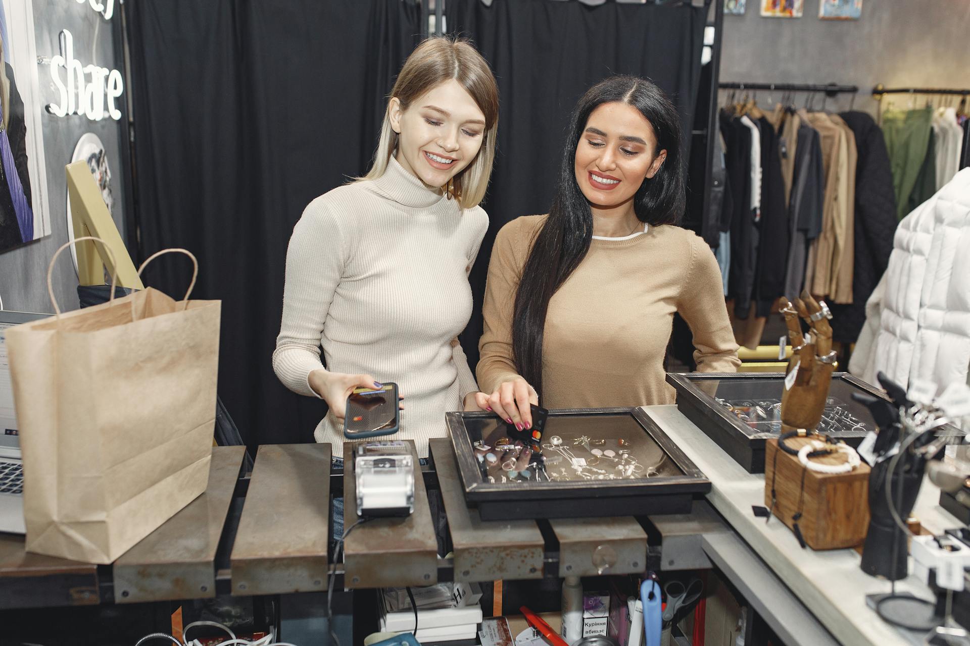 Two women making contactless payment in a chic fashion boutique.