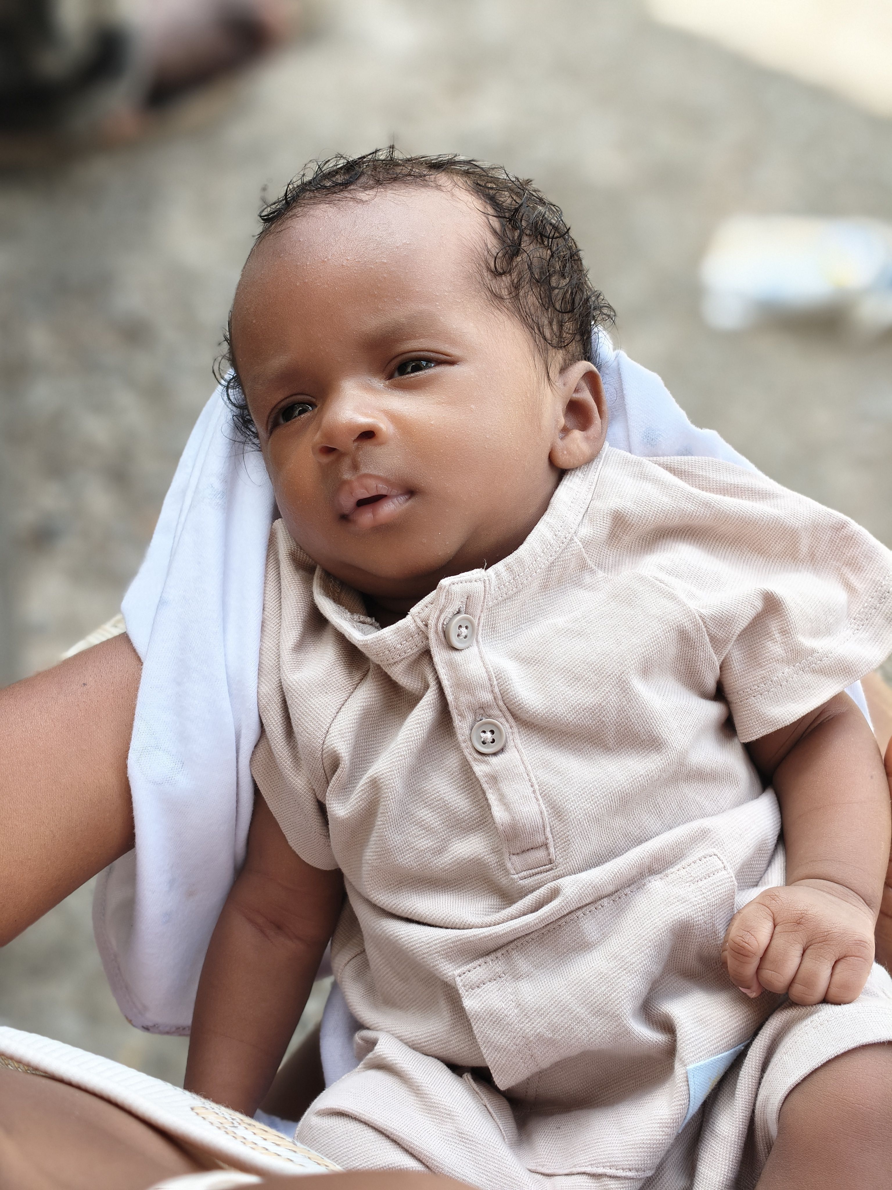 Charming portrait of a baby wearing a beige outfit, gazing thoughtfully outdoors.