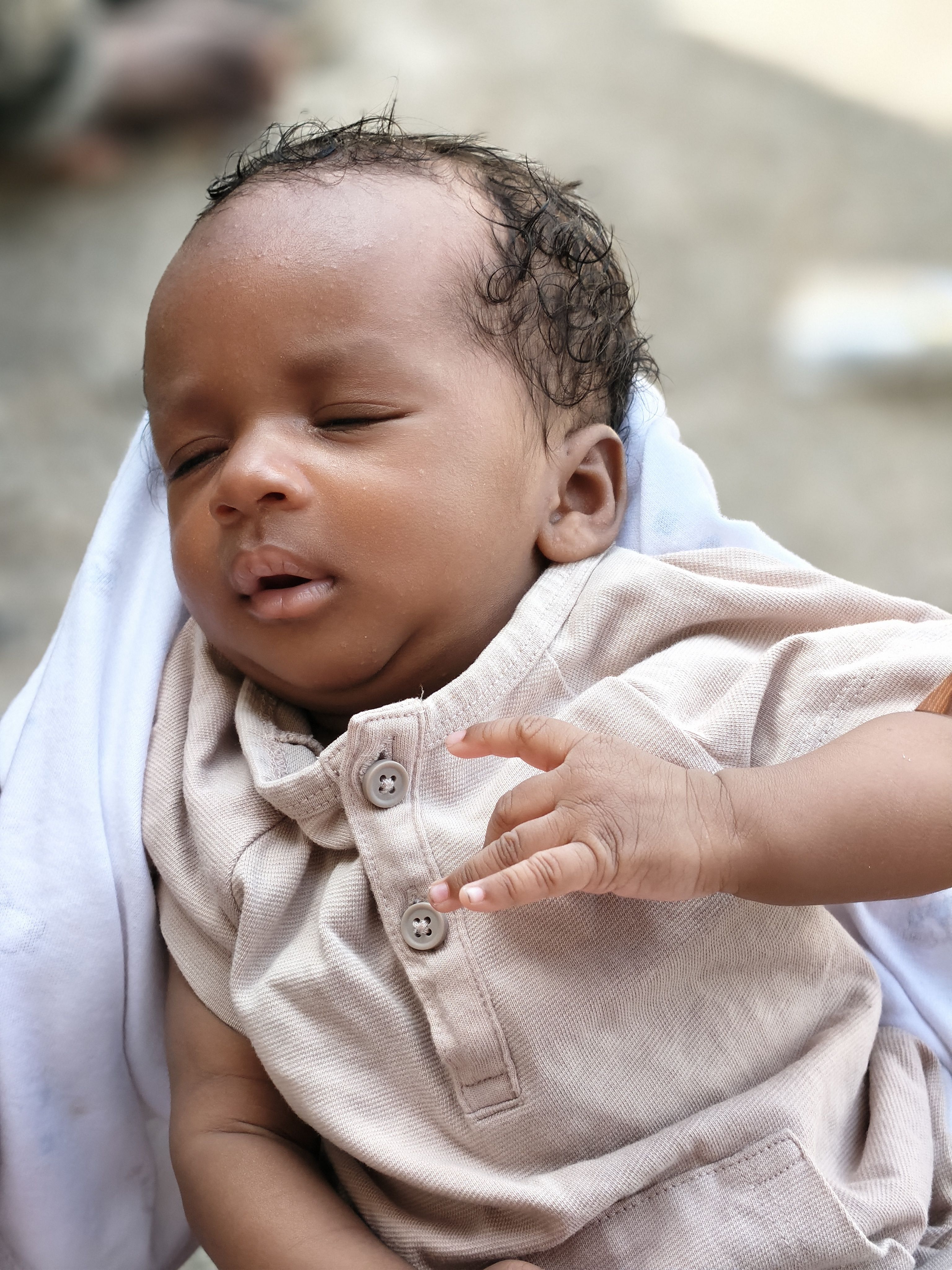 A peaceful baby resting comfortably wrapped in a blanket, enjoying the outdoors.