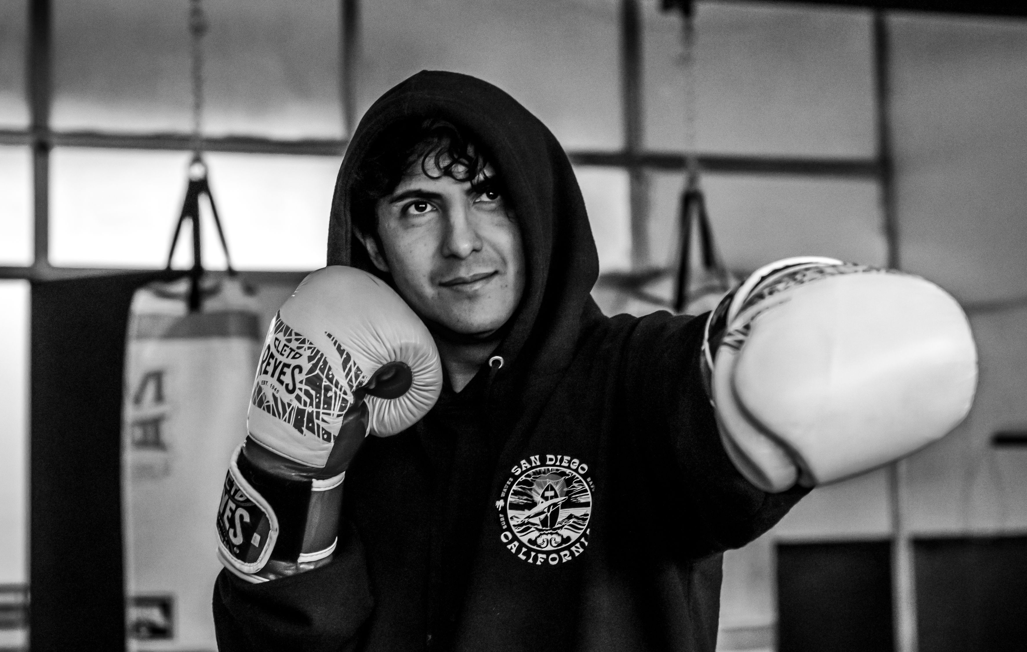A young boxer wearing gloves practices in a gym, focusing on technique and form.