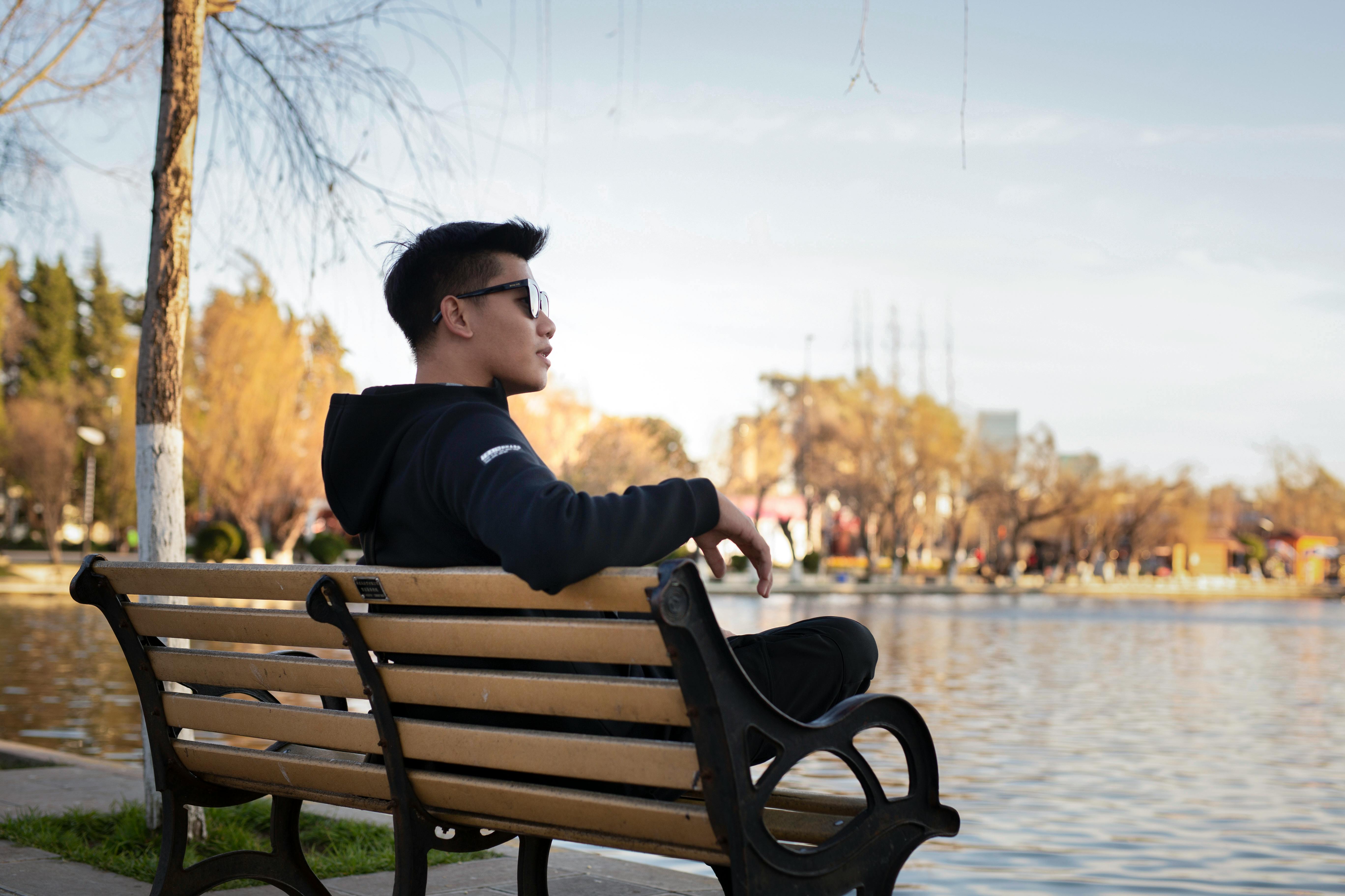 A man relaxing on a bench by the lake in Kunming, China during a sunny day.