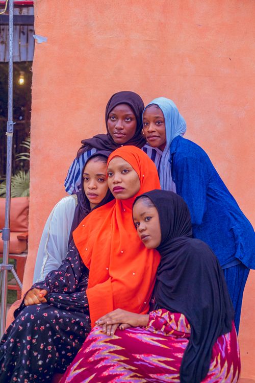Free Five young women in colorful hijabs posing against a warm backdrop in Rayfield, Nigeria. Stock Photo