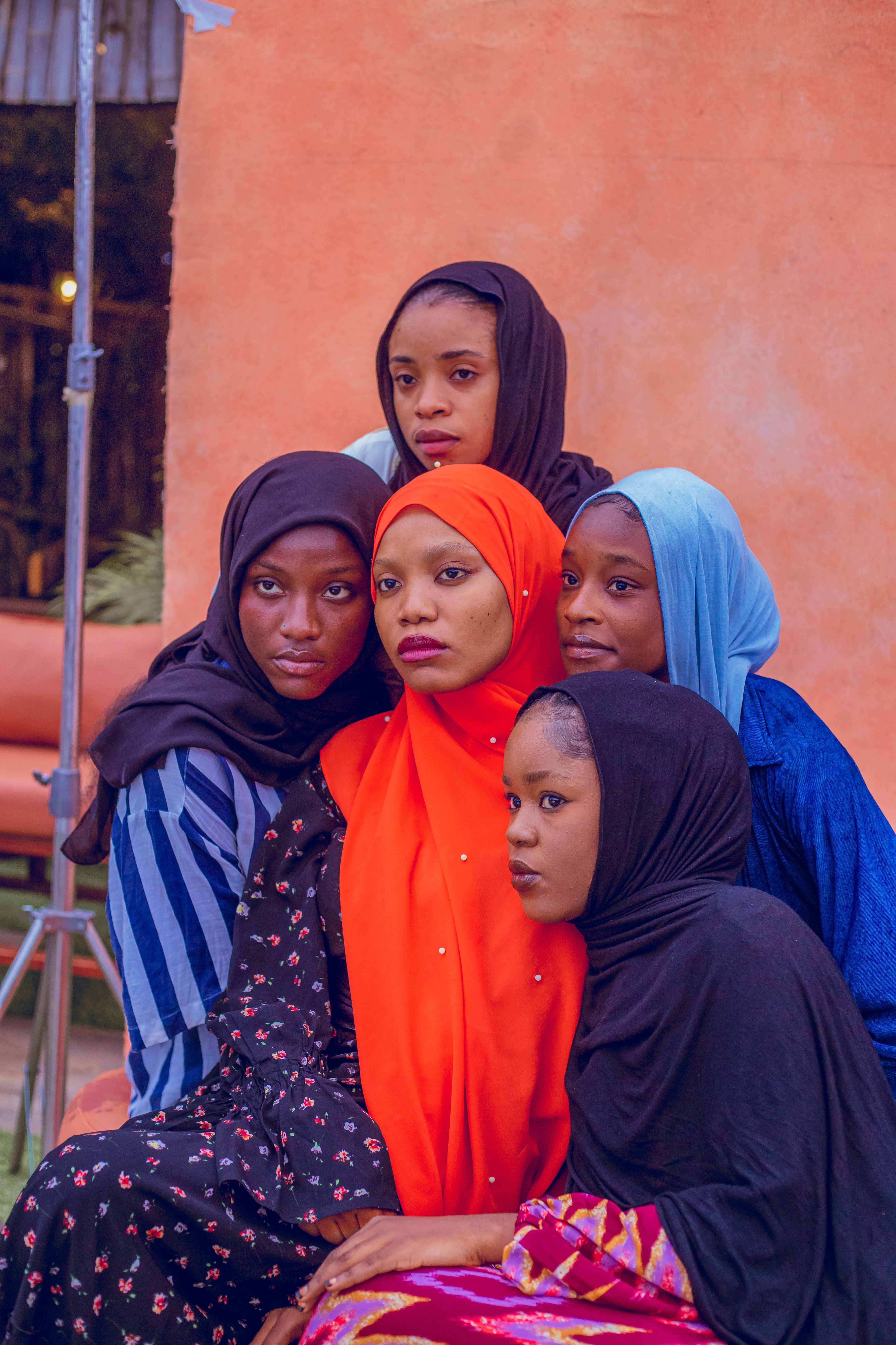 A group of young women wearing colorful hijabs poses together outdoors.