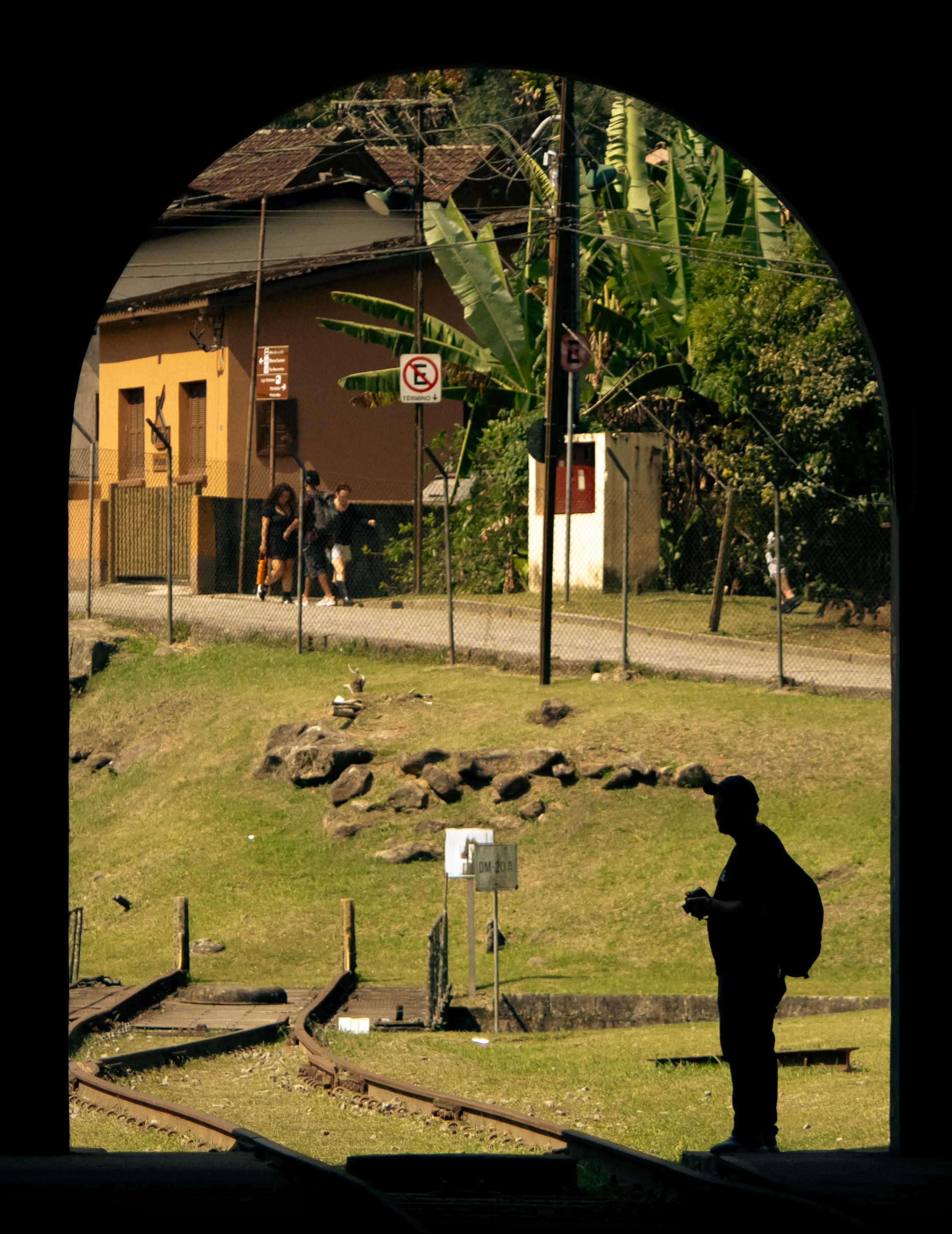Silhouette of a person framed by a tunnel, capturing Paranapiacaba's rustic charm and railway track.