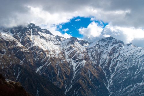 Free Dramatic snow-capped mountains and cloudy sky create a stunning winter landscape. Stock Photo