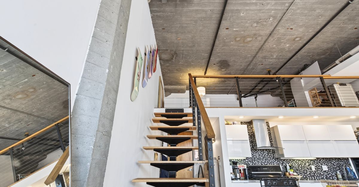 Explore a stylish Boston loft with an industrial aesthetic, open staircase, and modern kitchen.