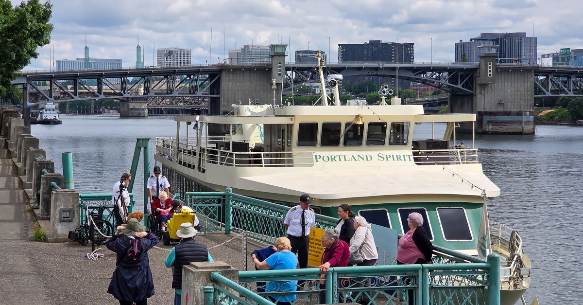 Cruise ship Portland Spirit docked by the Willamette River with people boarding.