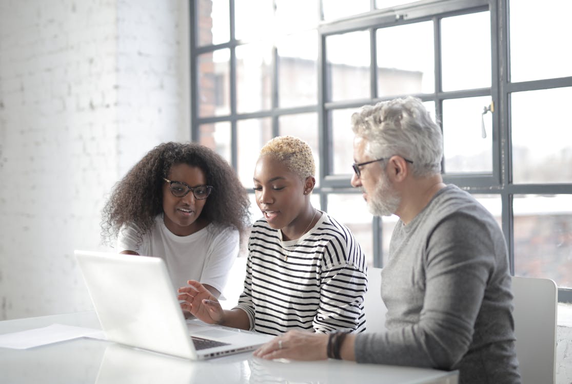 Concentrated multiracial coworkers working on laptop in modern workspace